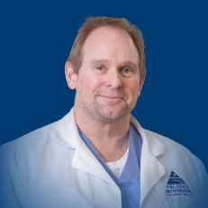 Dr. Glenn Johnson white coat headshot blue background